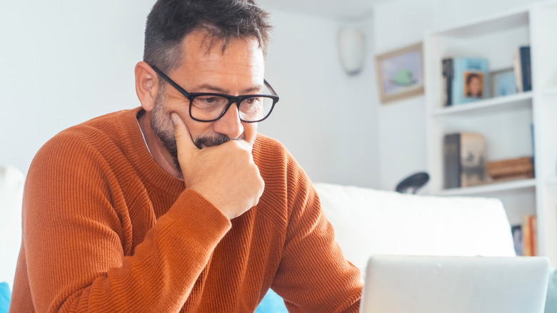 A man using a laptop to browse and research products online.