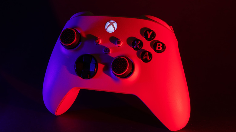 An Xbox Series X controller with its logo button brightly lit against a dark background.