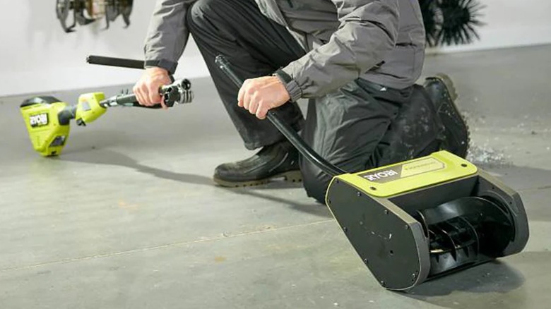 A person connecting the Ryobi power head to the snow thrower attachment.