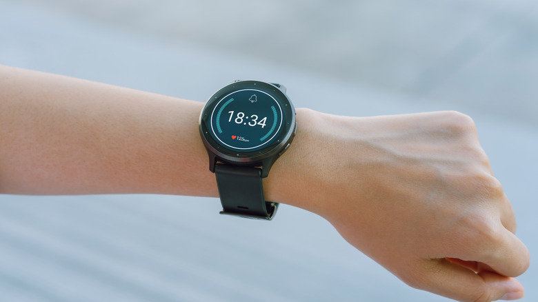A smartwatch on a person's wrist displaying time and live heart rate data clearly.