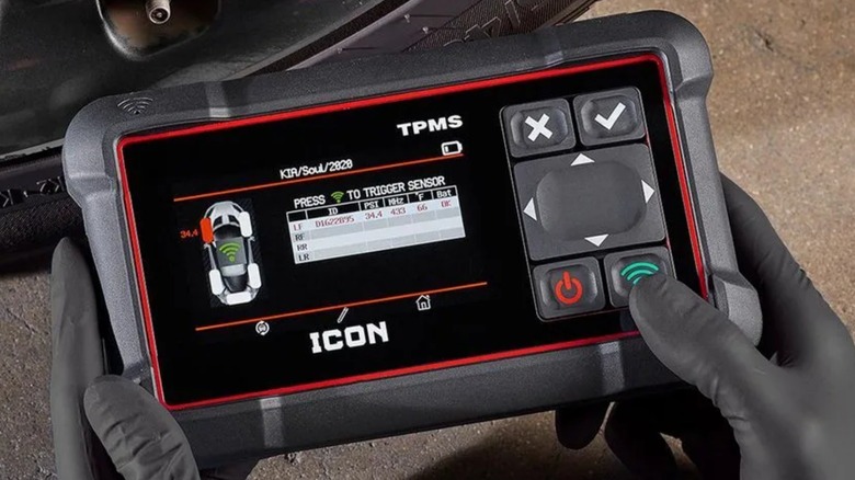 A mechanic using the handheld Icon Professional TPMS Diagnostic Tool on a vehicle tire.
