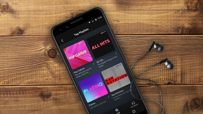 A smartphone showing the Amazon Music app with a pair of wired headphones plugged into the device.