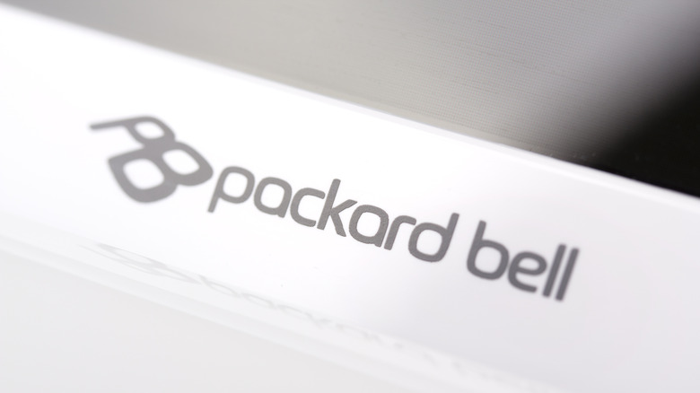 A close-up photograph of the Packard Bell brand logo on a tan plastic computer case.