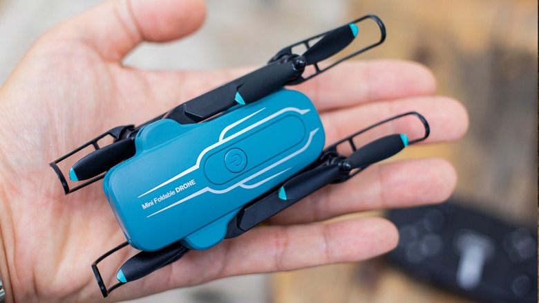 A person holding the Oviliee S17 mini drone in the palm of their hand to show its small size.