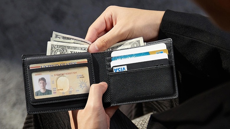A person pulling cash out of an ESR Geo Wallet which features built-in Find My tracking.