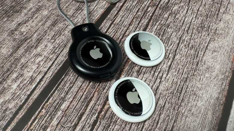 Several first-generation Apple AirTags sitting on a wooden table.