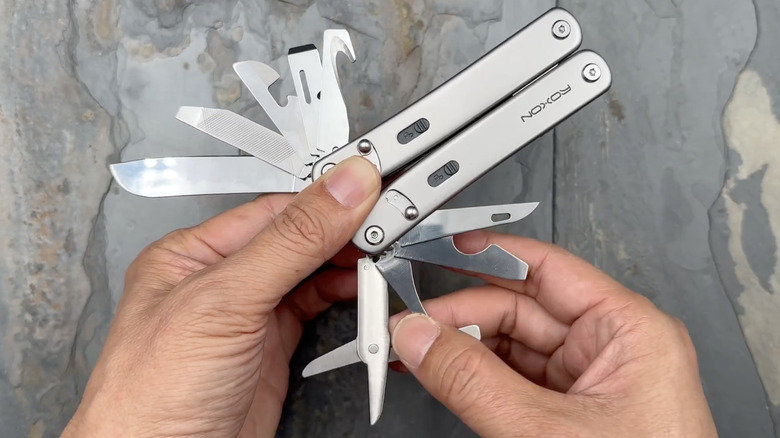 A person holding a Roxon Flex multitool with several custom-selected implements partially deployed.