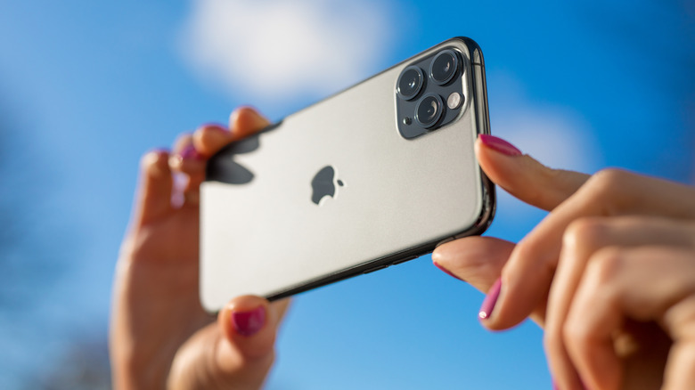 Close-up of a person using an iPhone camera to take a photograph.