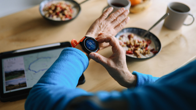 A person checking their health metrics on an Apple Watch while sitting at a kitchen table.