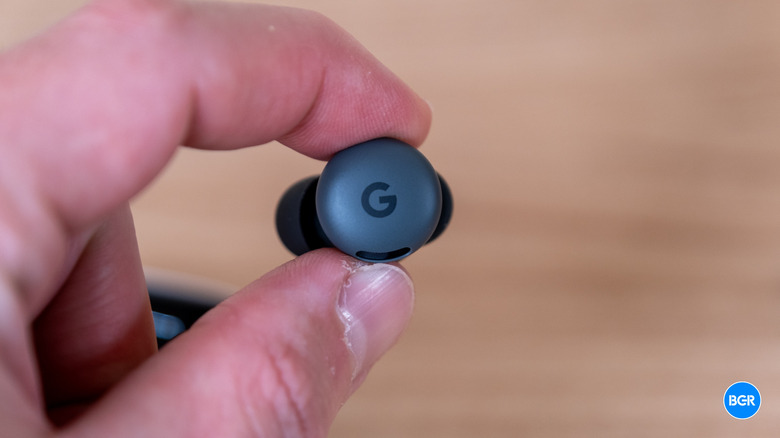 Close-up detail of a single Google Pixel Buds 2a earbud showing the 'G' logo and charging contacts.