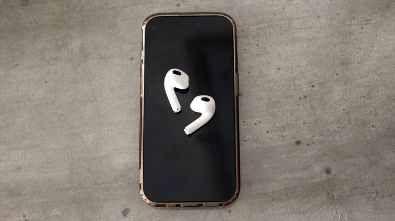 Wireless AirPods and an iPhone arranged on a wooden surface.
