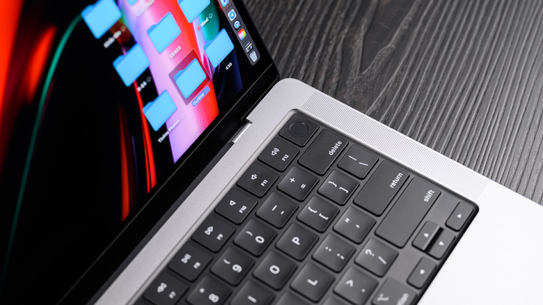 Close-up of an open MacBook Pro displaying its desktop on a dark wooden surface.