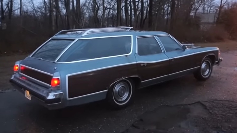 A blue and brown Pontiac Grand Safari station wagon with wood-grain side paneling parked in a driveway.