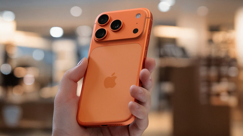 A person holding an orange iPhone 17 Pro Max at an angle.