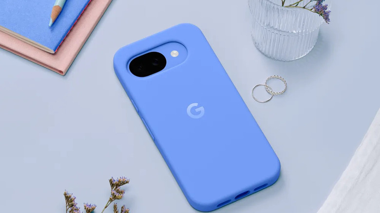 Blue Google Pixel 10a smartphone inside its blue silicone case on a light blue surface.