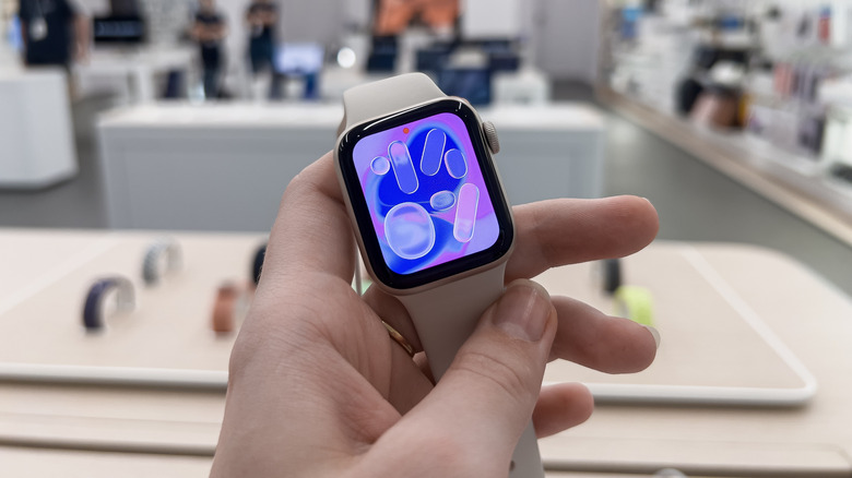 Apple Watch SE 3 held in hand with the bright display turned on.