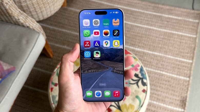 Close-up of a hand holding an iPhone with a bright OLED screen.