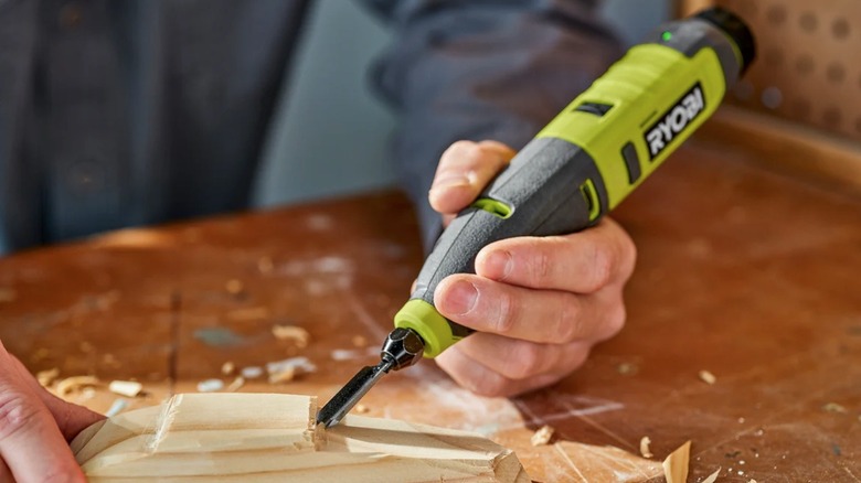 A hobbyist using a Ryobi 4V rotary tool to carve a piece of wood.