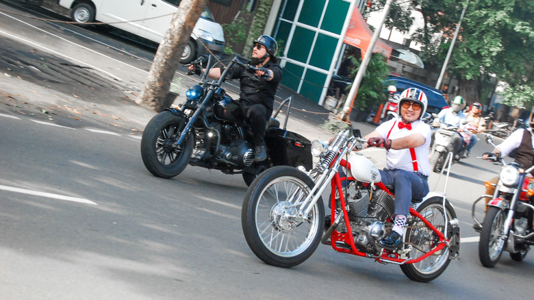 A group of custom motorcycles riding on a city street during the day.