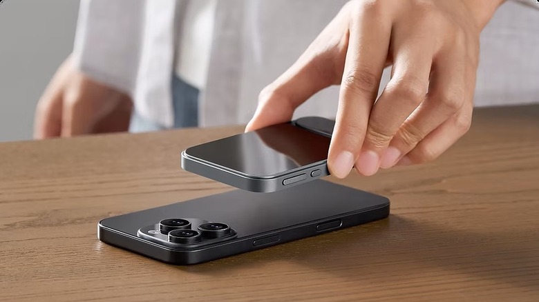 A hand holding the slim Khadas Tea Pro DAC about to snap it onto the back of an iPhone.