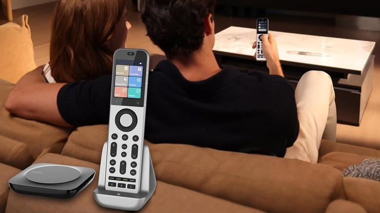 A couple sitting on a couch using a single advanced universal remote to control their TV.