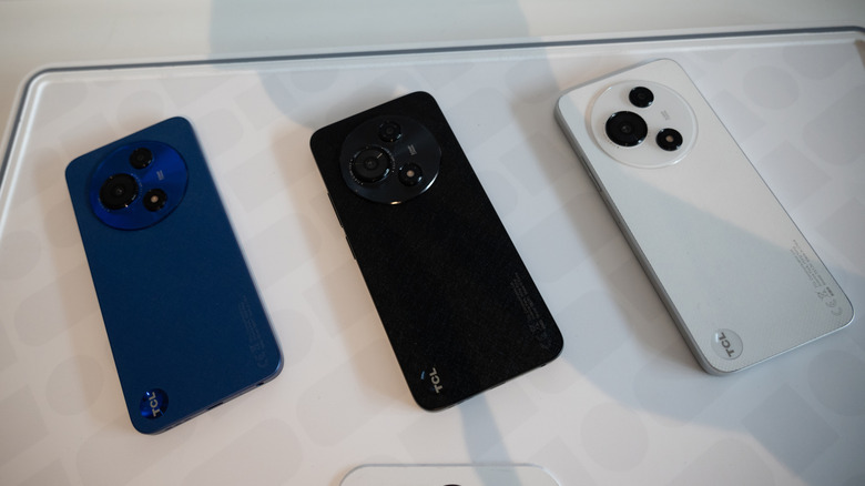 Three different TCL smartphones lined up on a surface to show design variety.