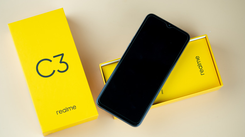 A yellow Realme brand smartphone and its characteristic yellow packaging box.