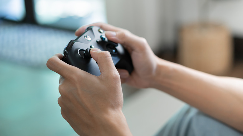 A person holding a modern video game controller.